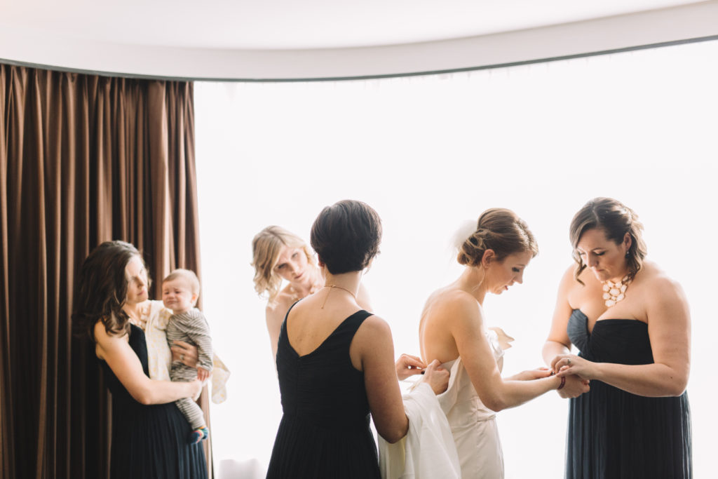 Bride getting dressed with the help of bridesmaids