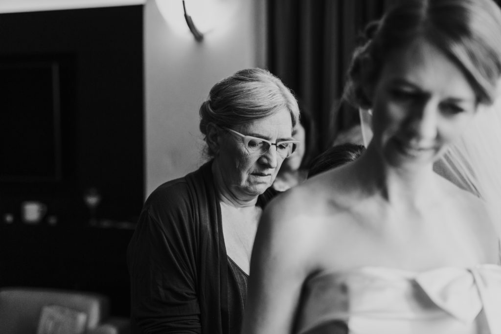 Mother of the bride helping bride get into wedding dress