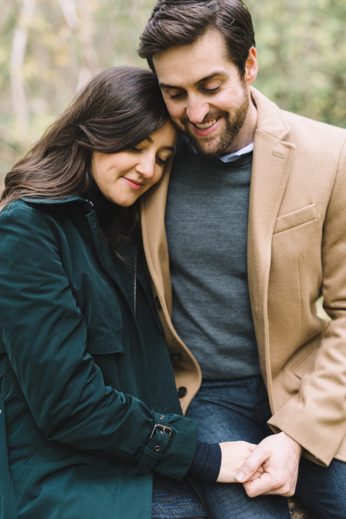 Couple cuddling and and holding hands in Mill Pond Engagement Session