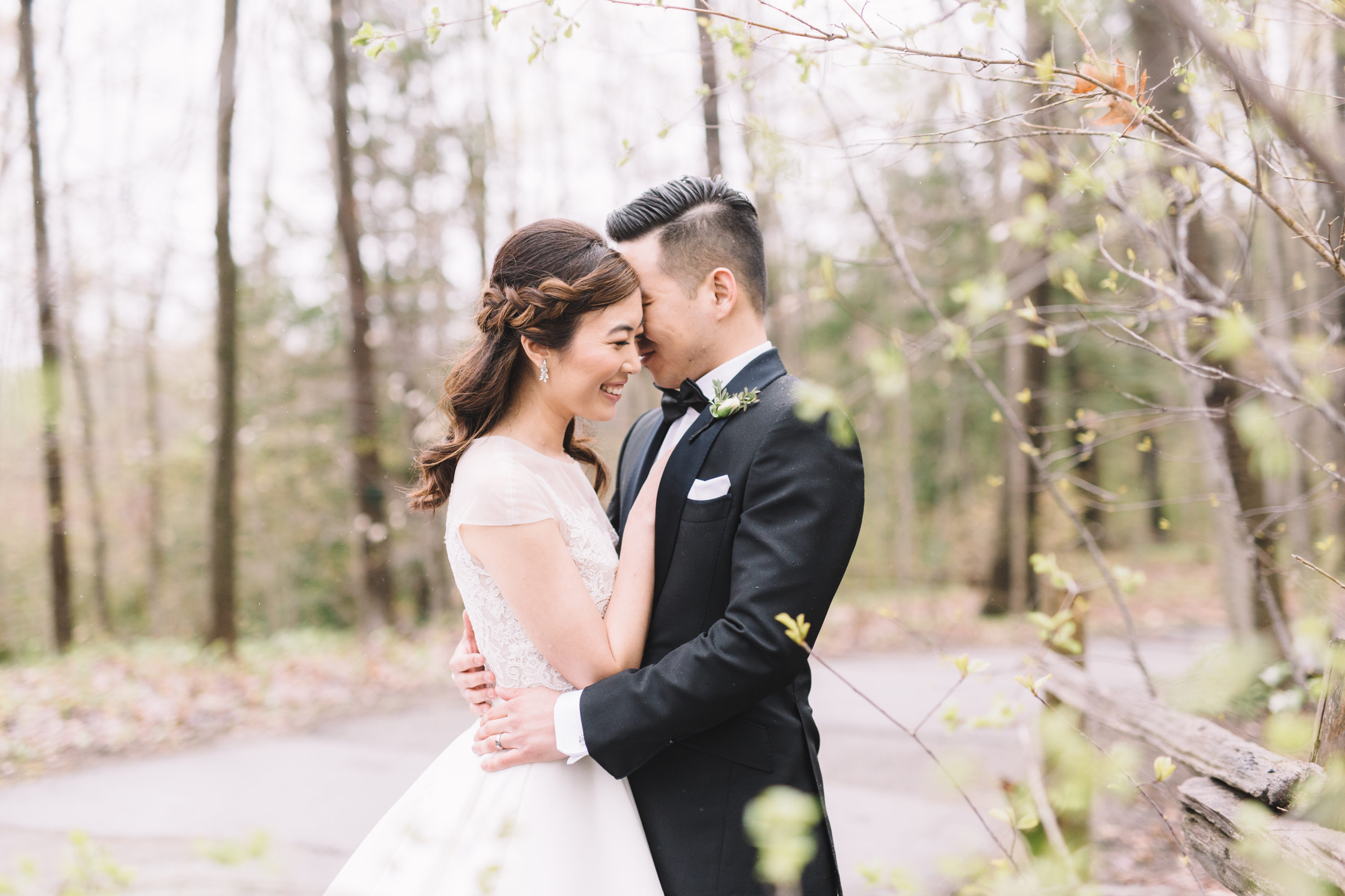 Bride and groom snuggling in rainy forest at Whistle Bear Golf Club