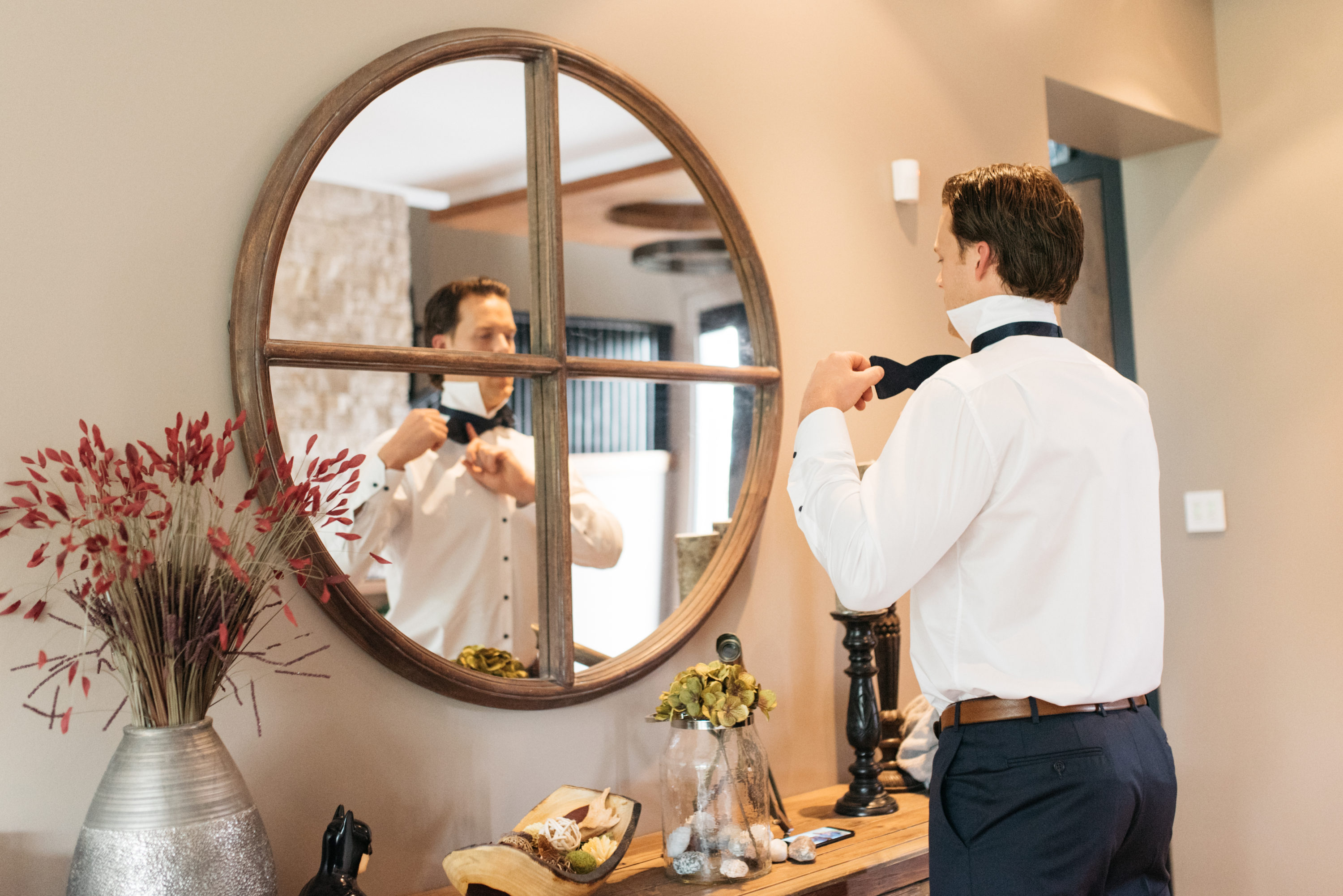 Groom putting tie on in mirror
