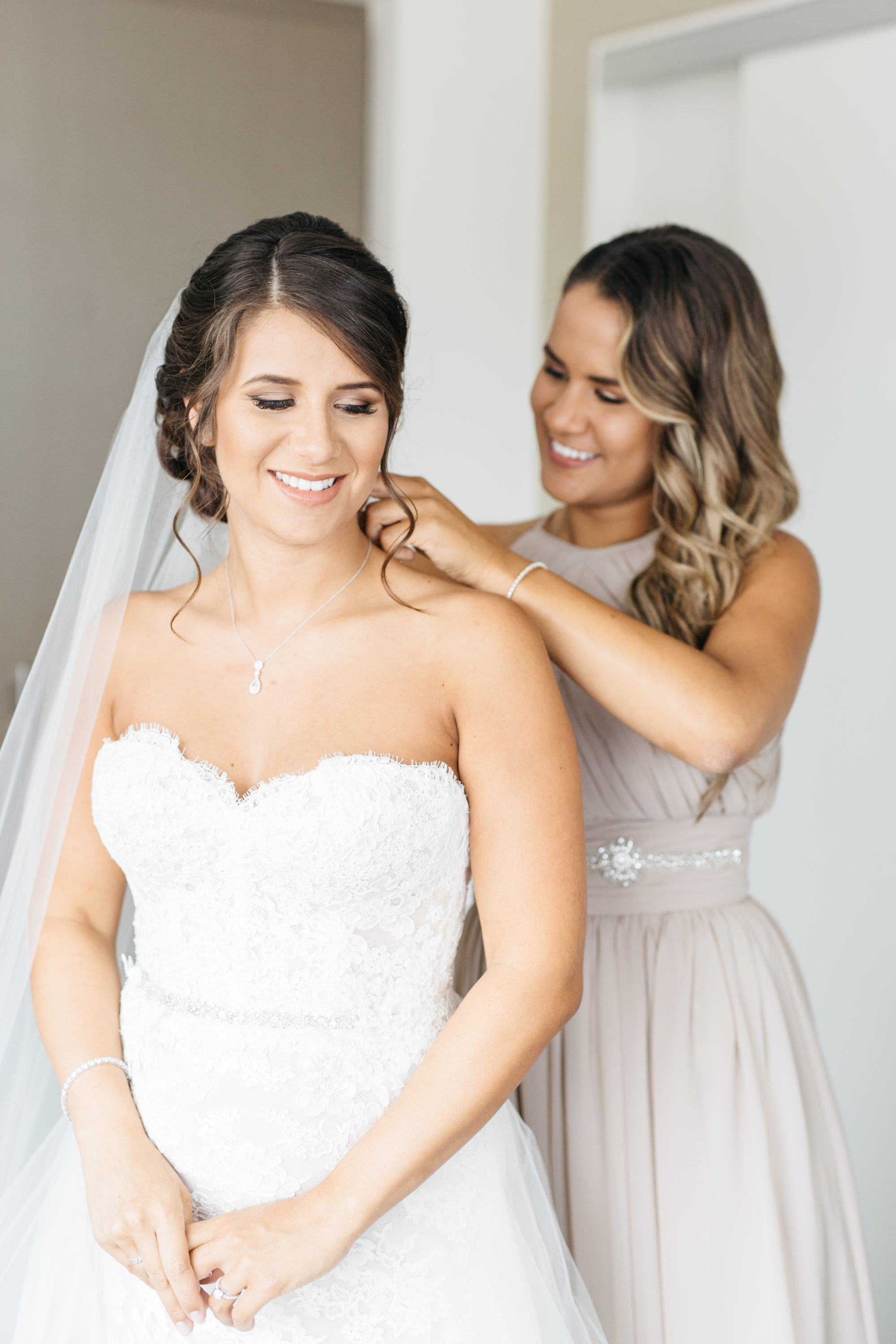 Maid of honour helping bride with jewelry