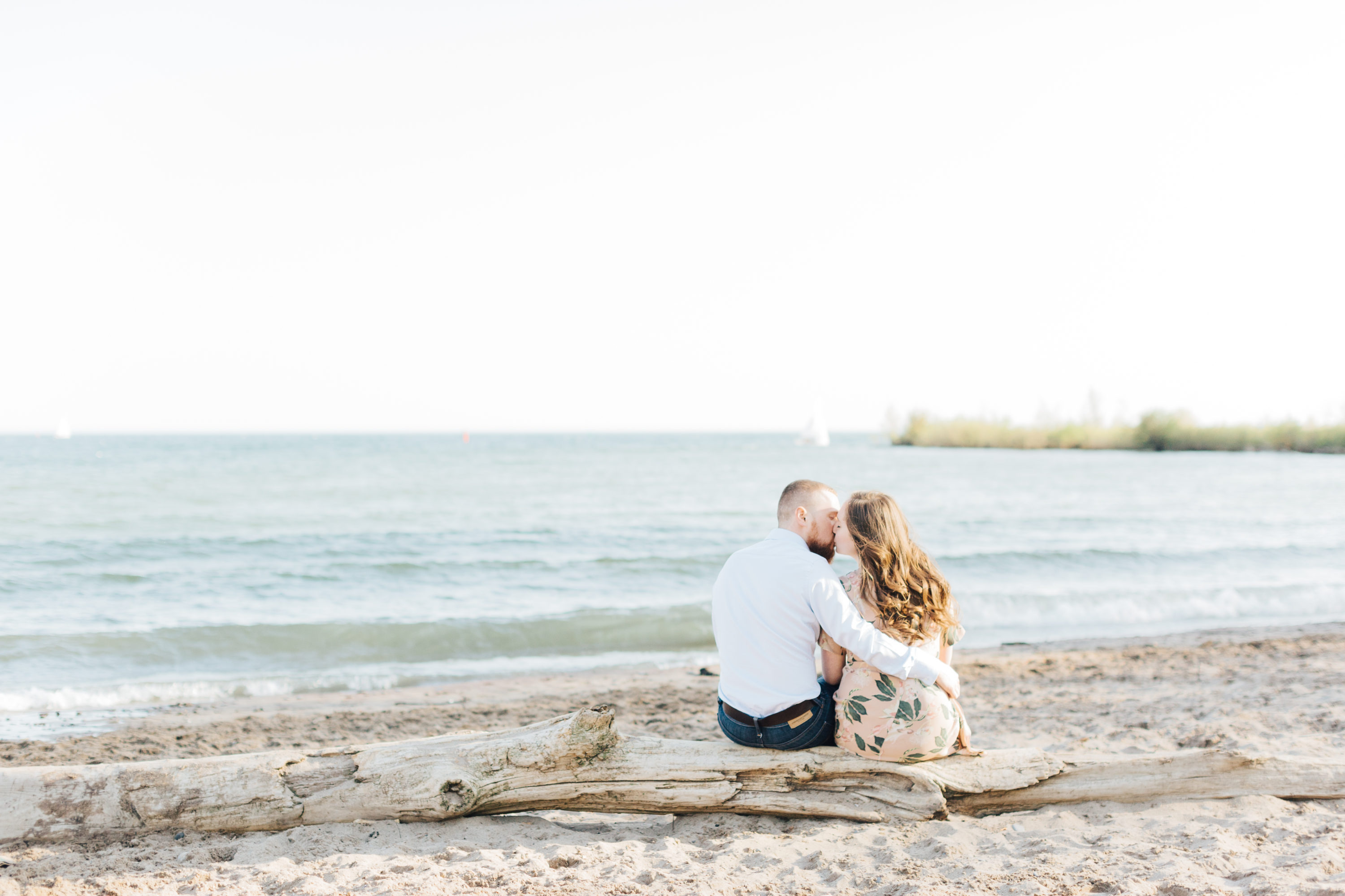 Couple sitting and kissing at Cherry beach for engagement photos