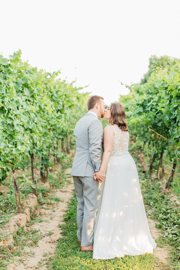 Bride and groom kissing in vineyard at Stonewall Estates
