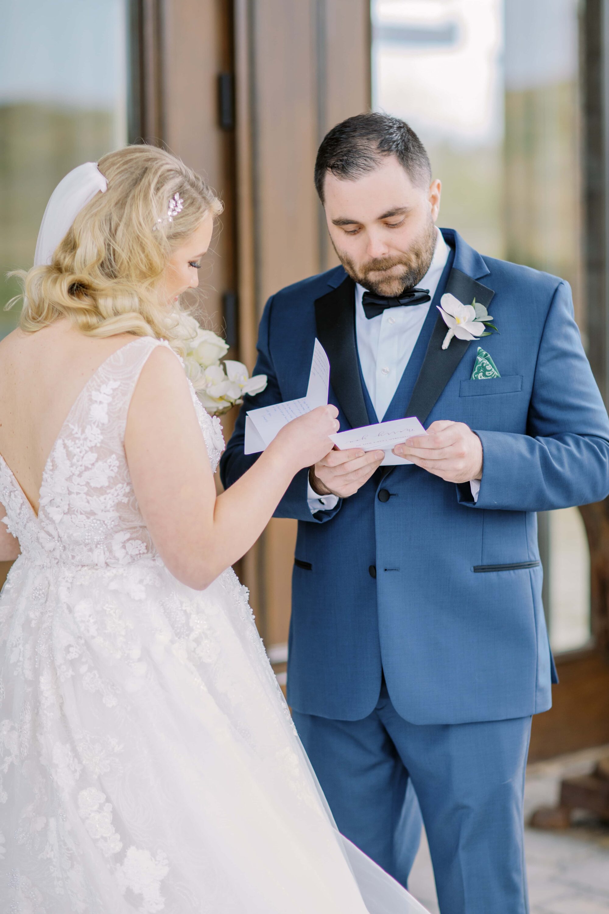 Bride and groom exchange handwritten letters, standing next to each other in front of oversized wooden doors