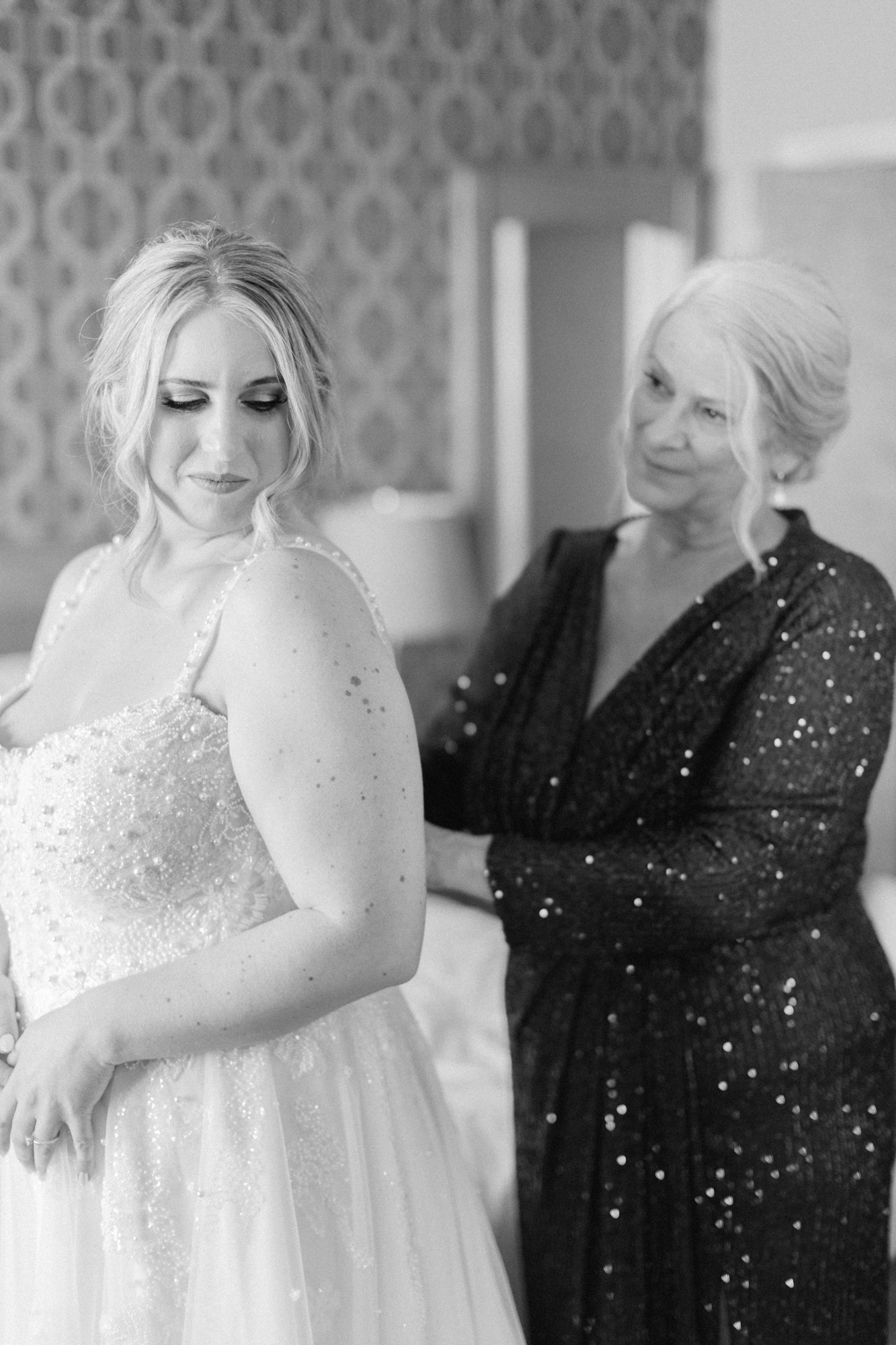 Bride's mom helping bride zip up dress