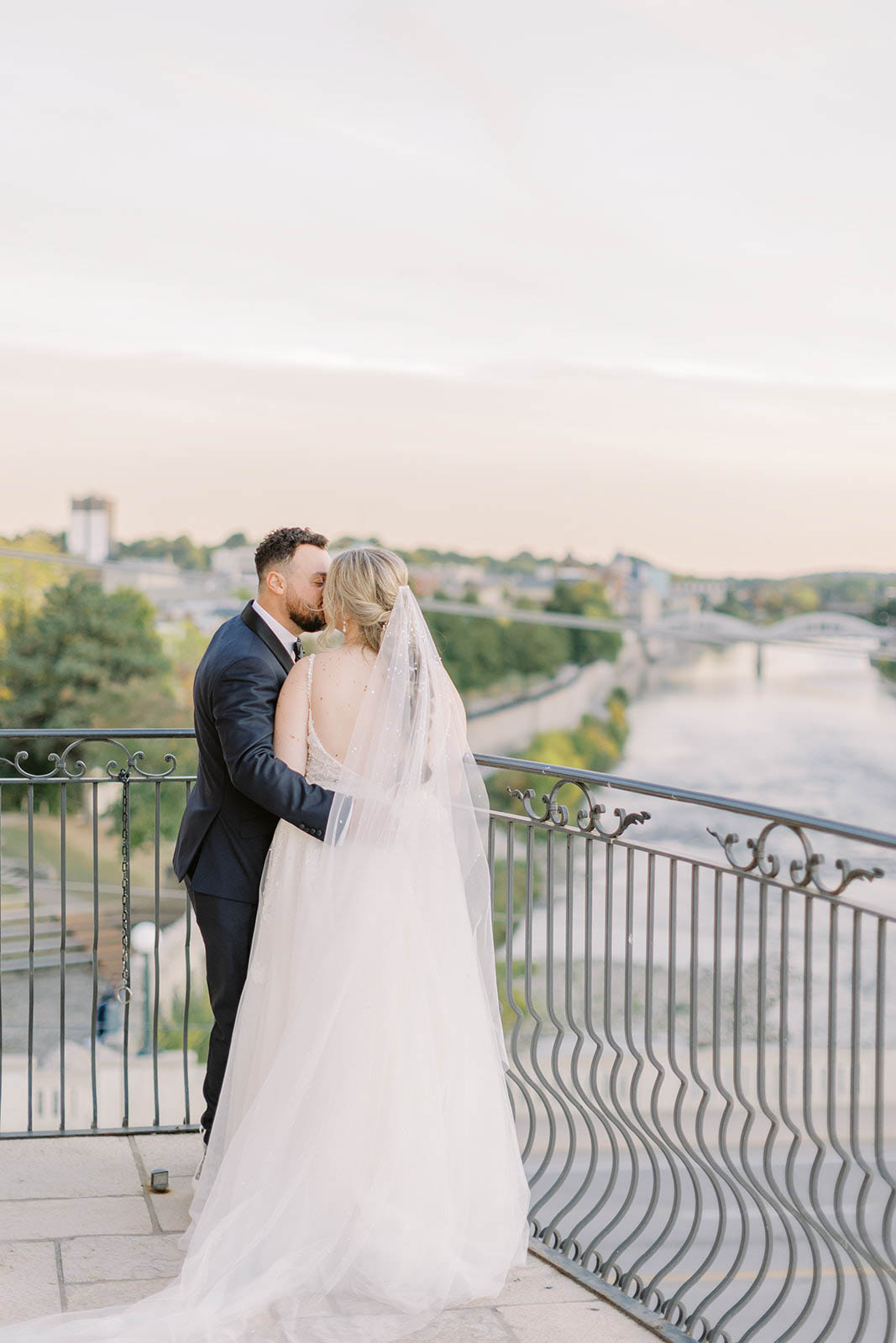 Bride and groom, kissing during sunset on balcony at Cambridge Mill wedding