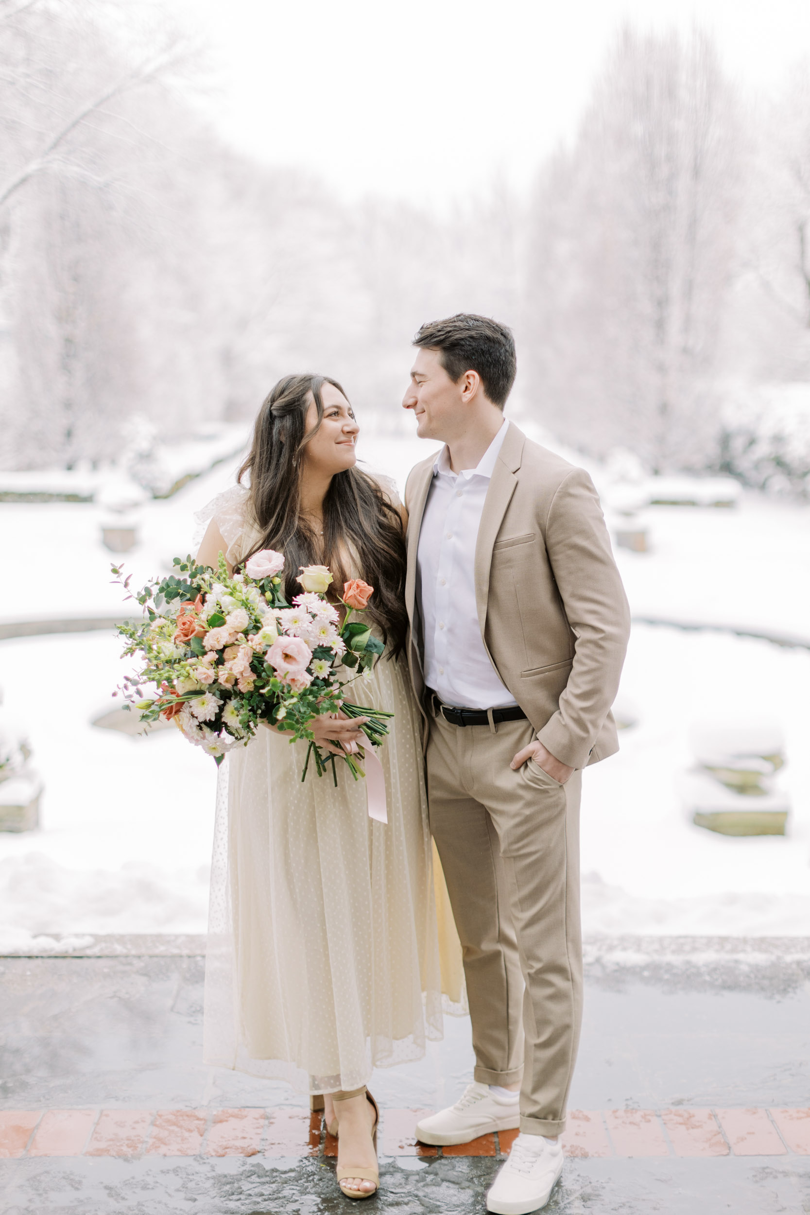Bride and groom smiling at each other in snowy backyard at Graydon hall