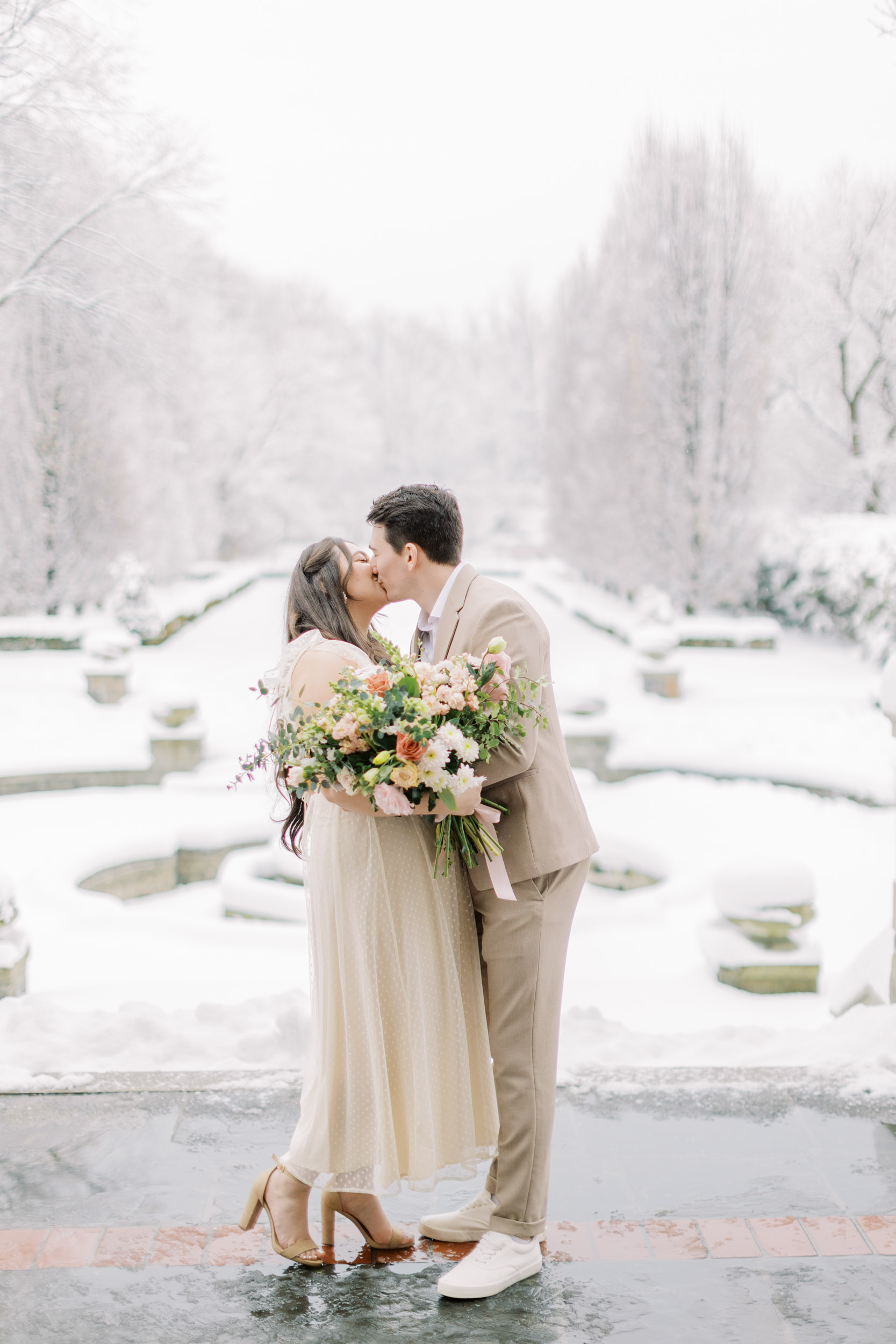 Bride and groom kissing in snowy backyard at Graydon hall