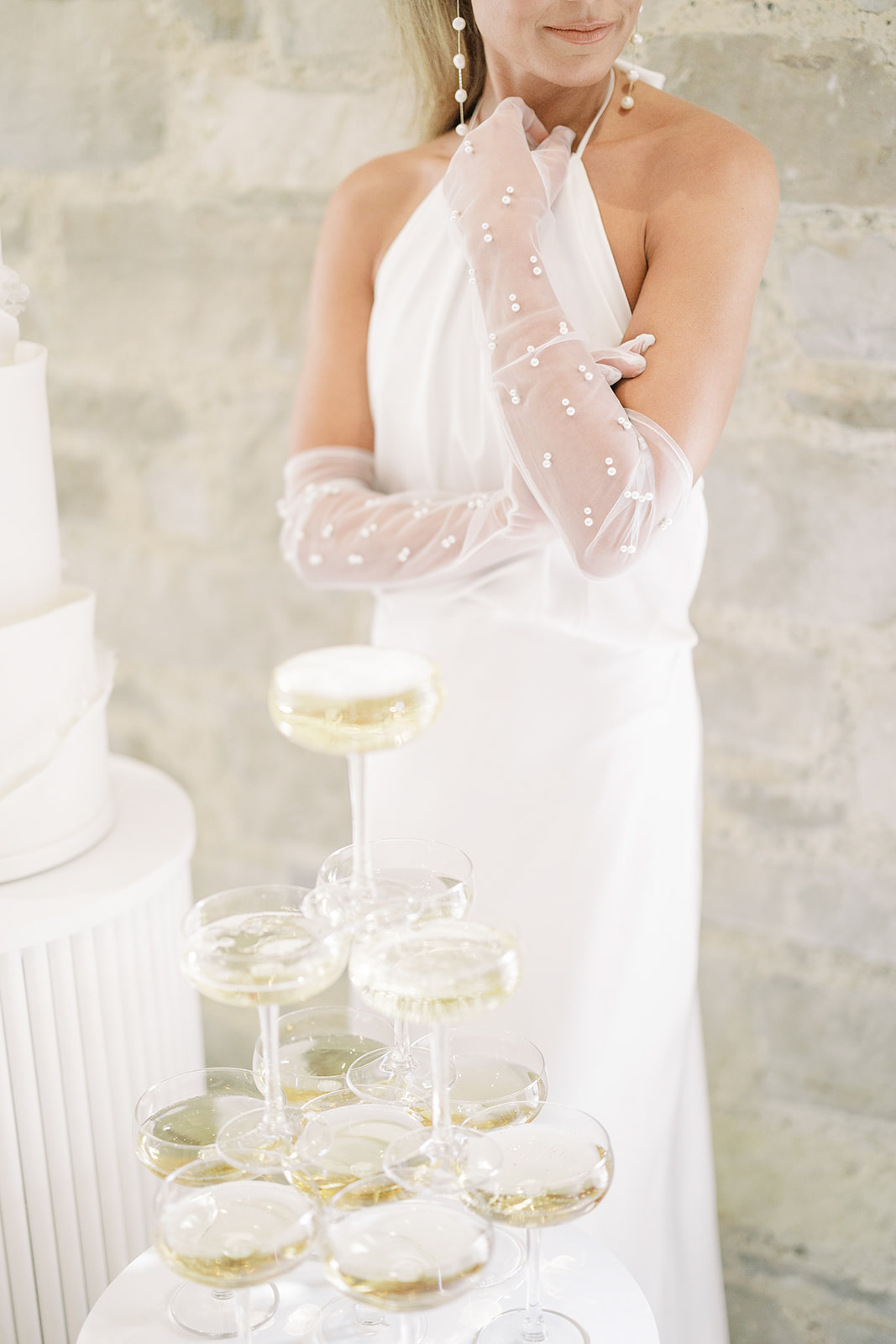 Champagne tower with bride standing beside it with pearl gloves on at Elora Mill