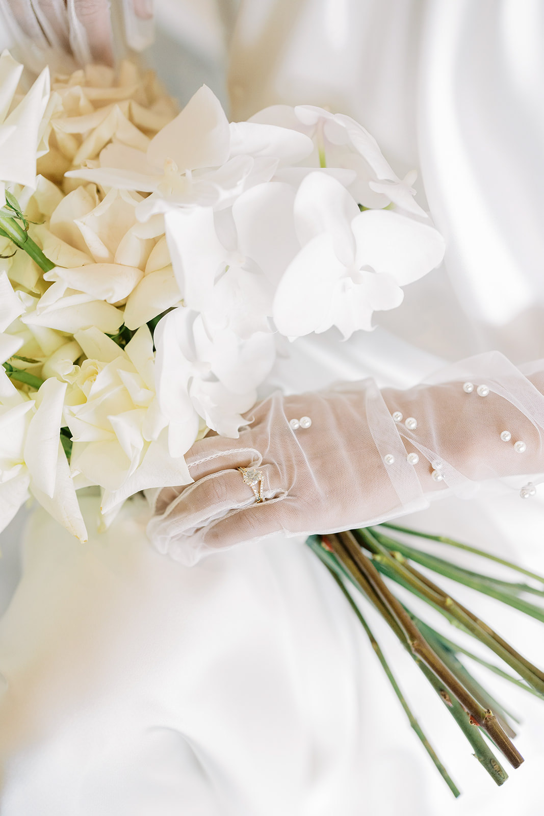 Close up photo of bride holding bouquet with pearl gloves on