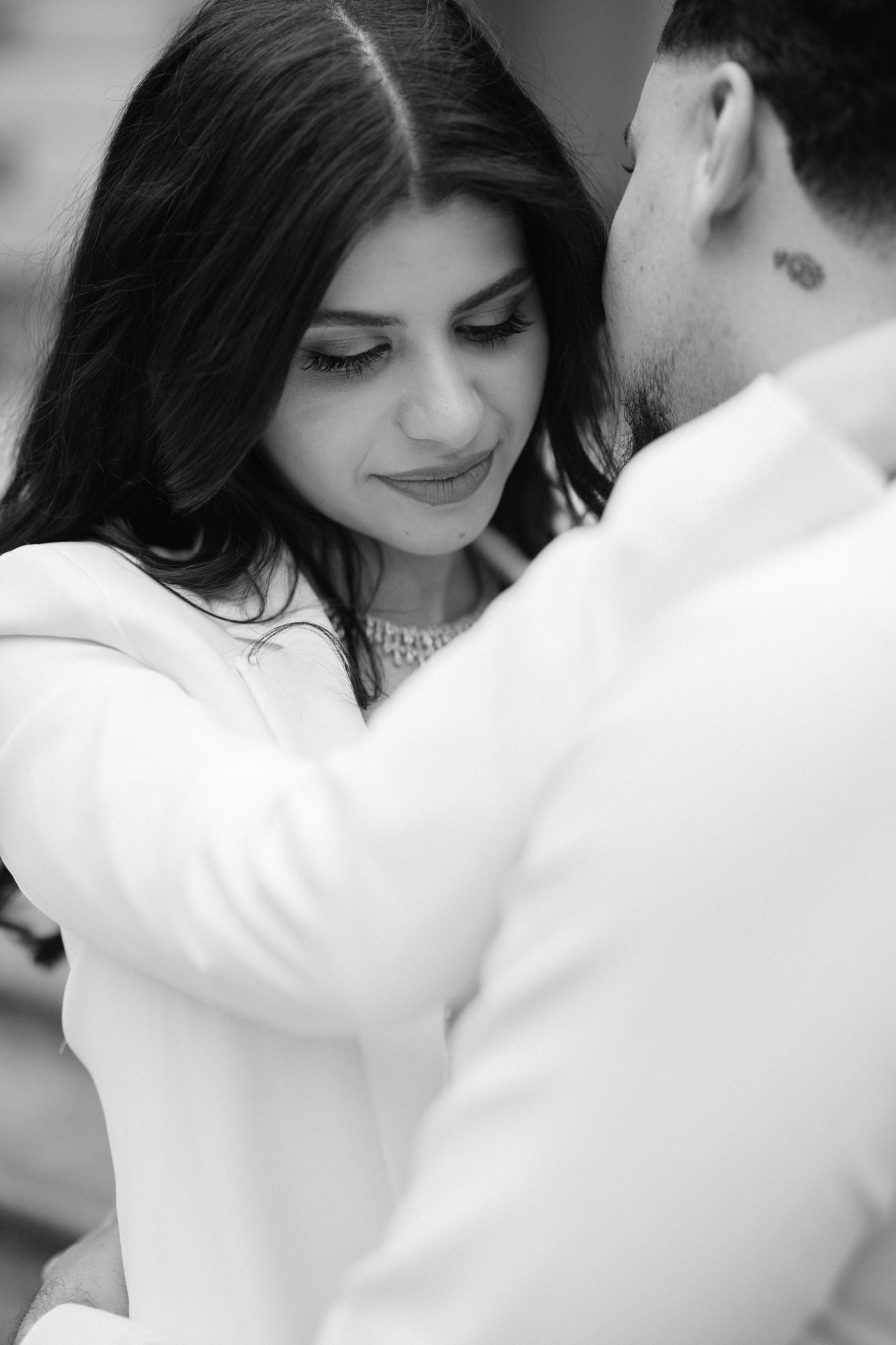 Black and white photo of groom-to-be whispering into fiancé's ear
