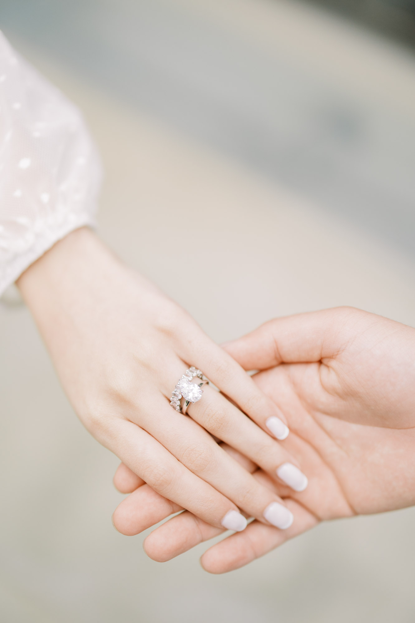 Close up photo of woman's hand with engagement ring holding fiancé's hand