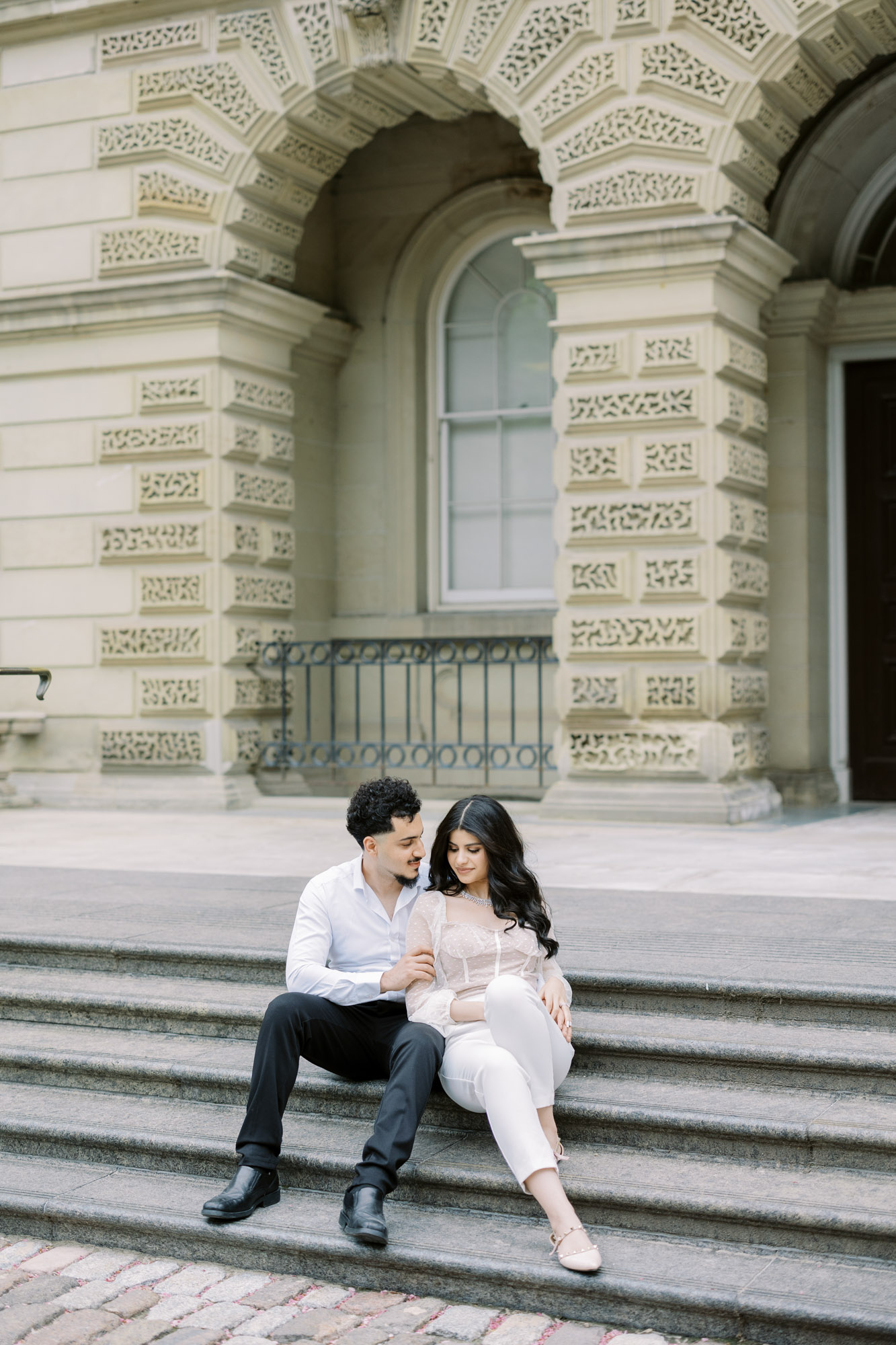 Couple sitting on the stairs at European inspired Osgoode Hall engagement session
