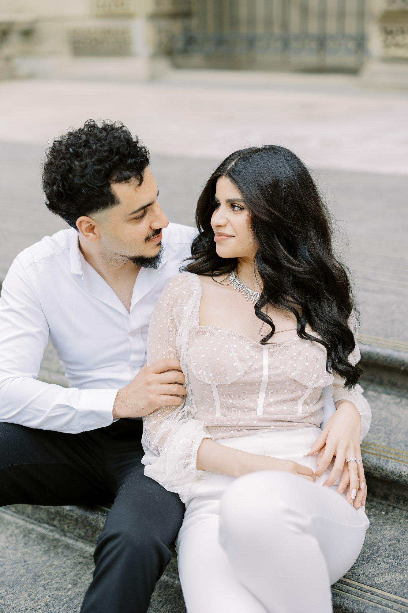 Couple sitting on the stairs looking at each other at European inspired Osgoode Hall engagement session