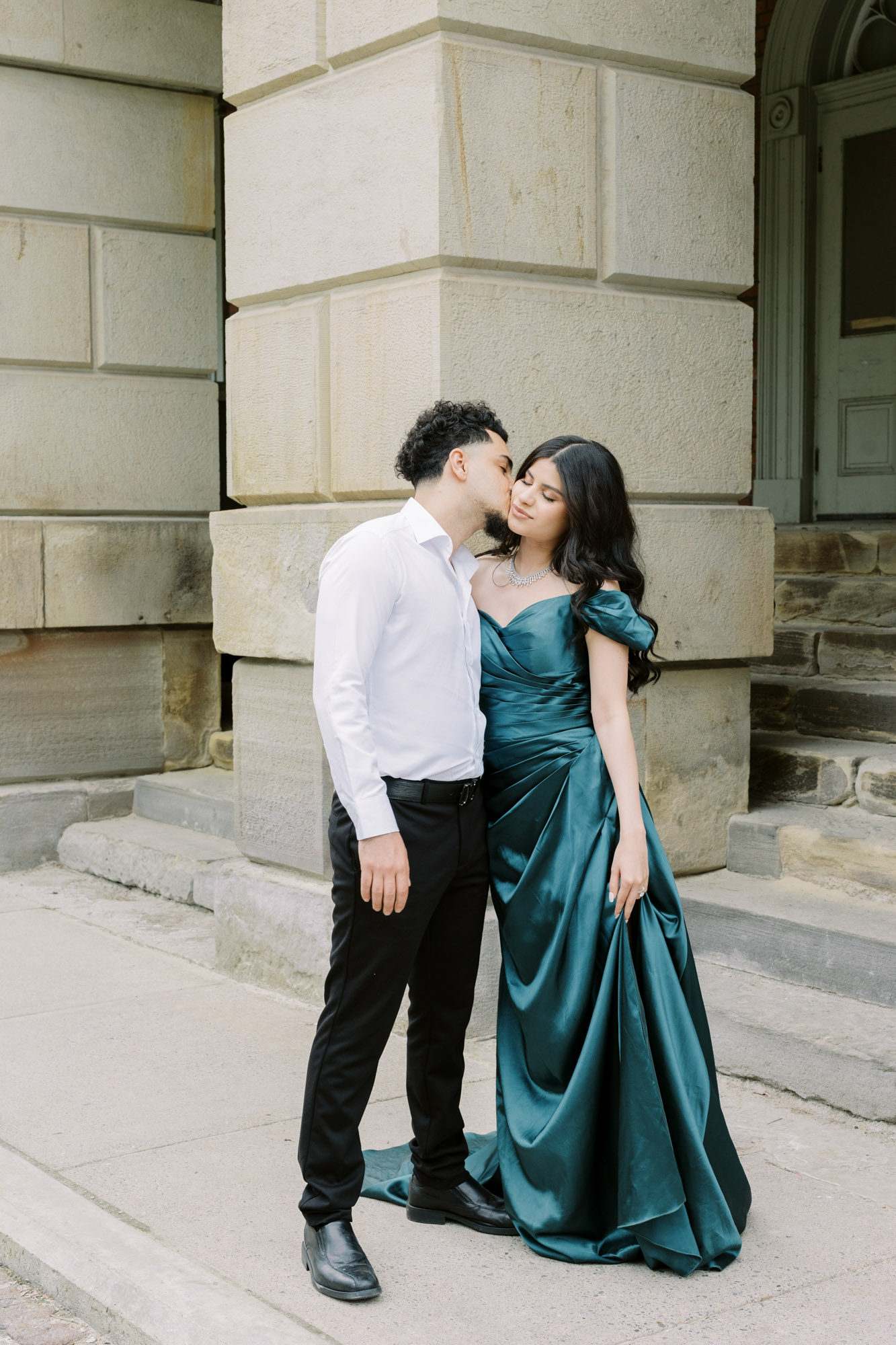 Man kissing fiancé on the cheek at engagement session