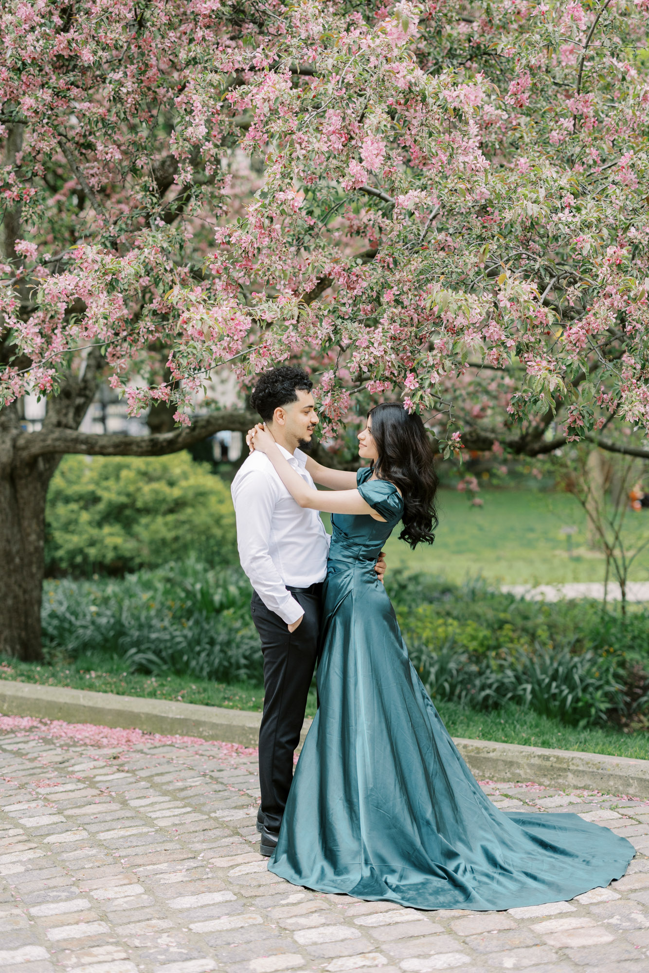 Couple holding on each other under a tree with pink flower blooms