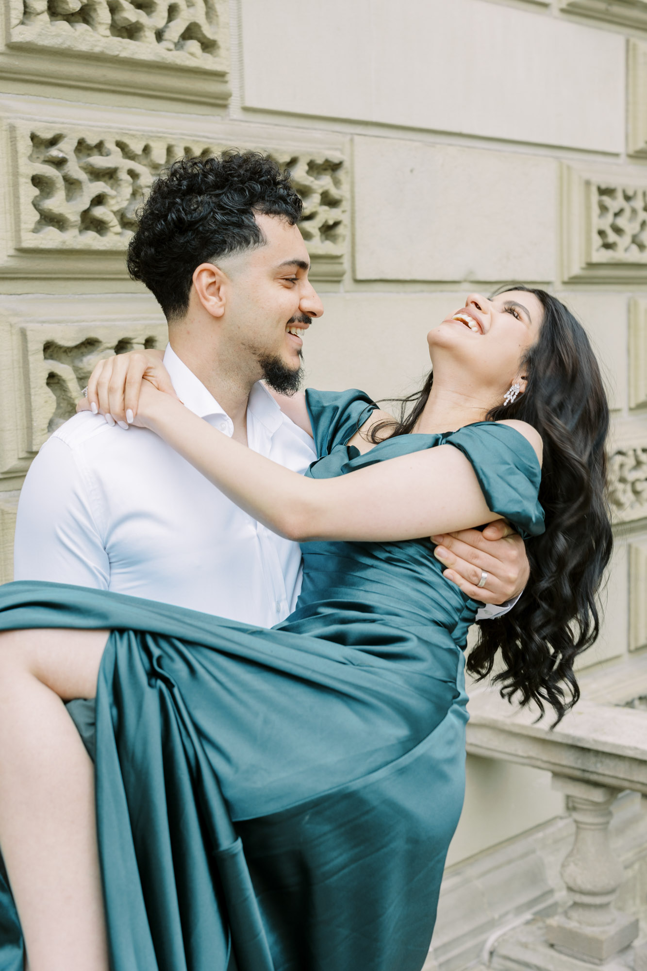 Man carrying fiancé at Osgoode Hall while she laughs