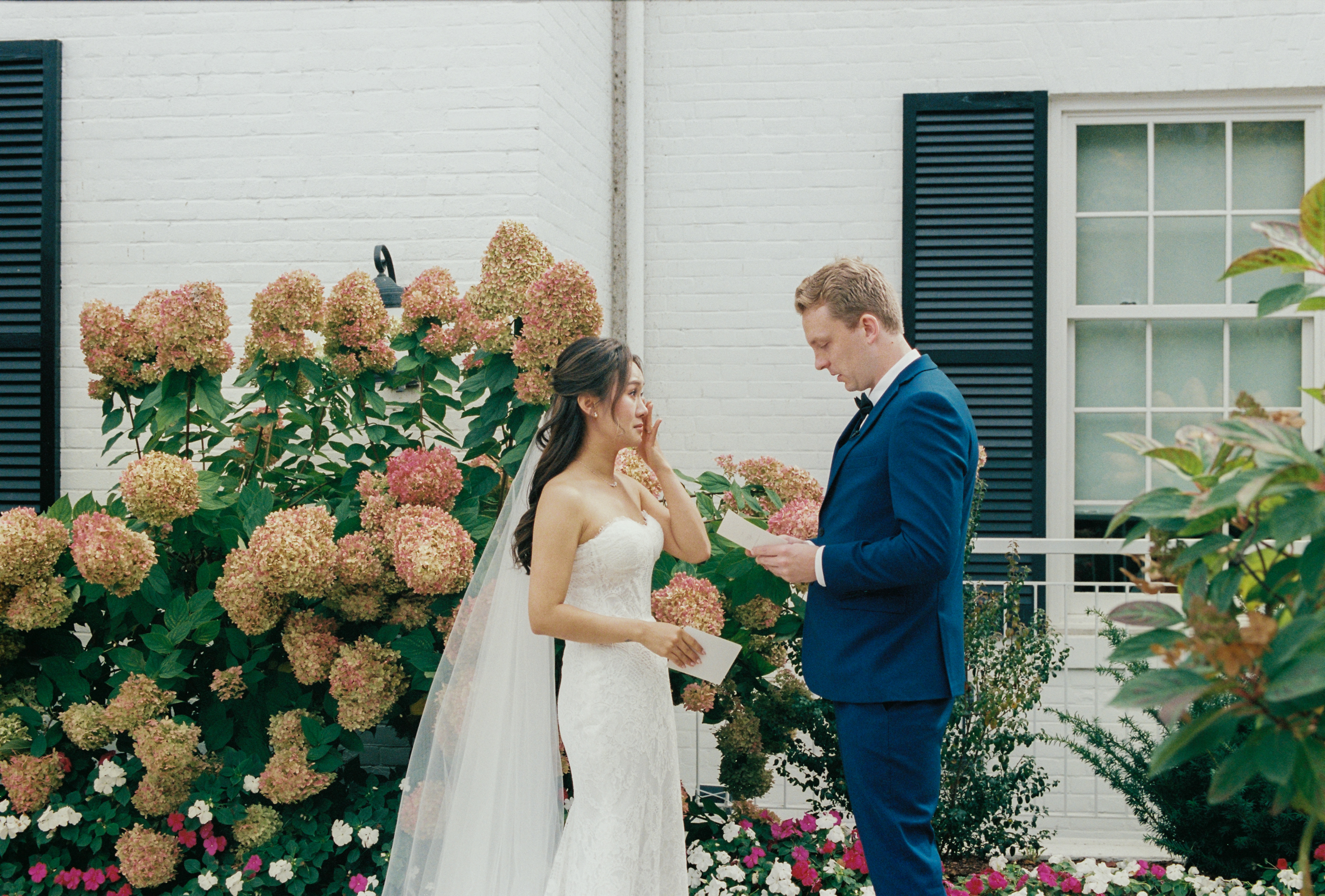 Film photograph of bride and groom reading letters outside of Harding Waterfront Estate 