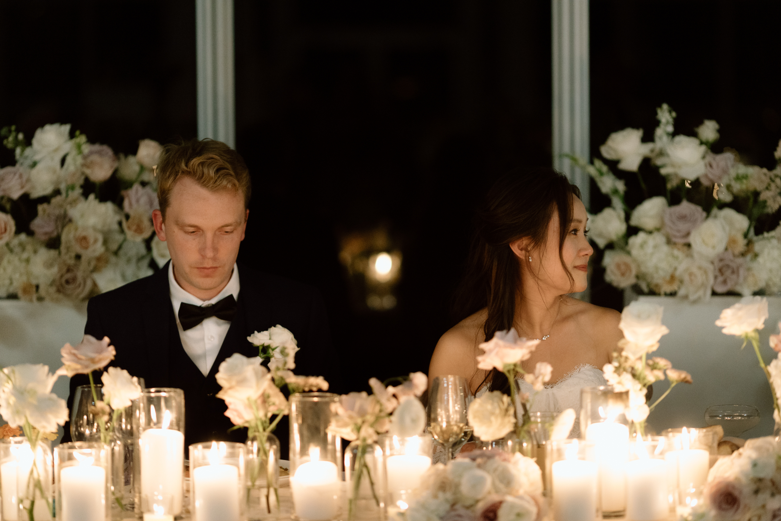 Bride and groom at head table inside glass pavillion at Harding Waterfront Estate 
